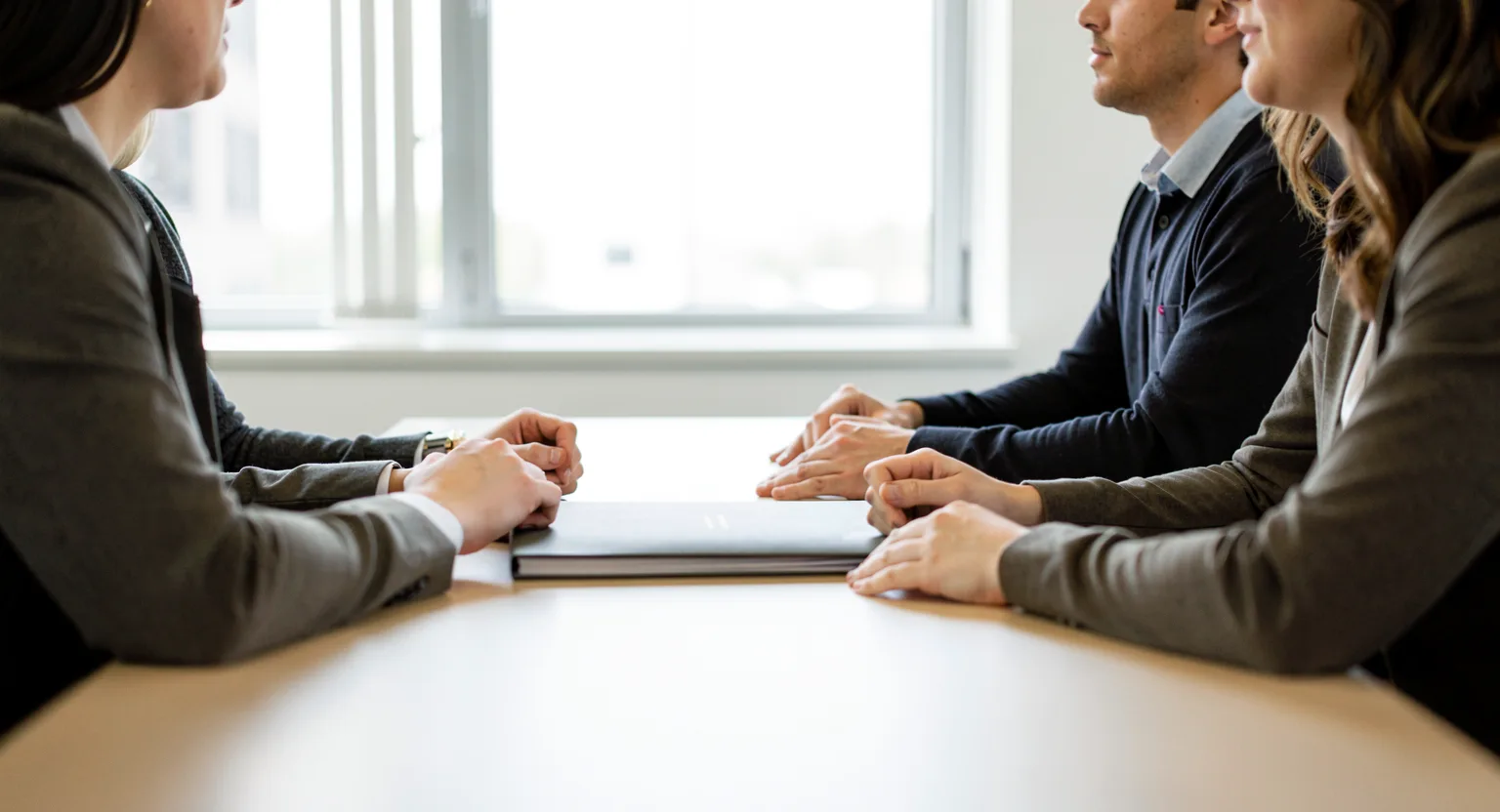 Trzy osoby przy stole w biurze podczas rozmowy