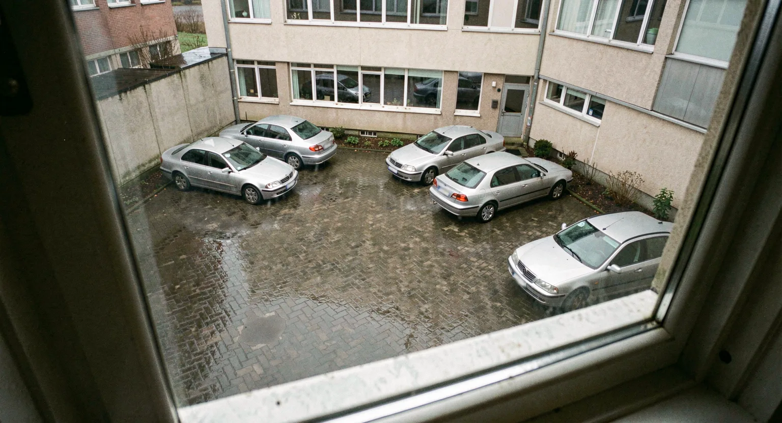 Kilka aut zaparkowanych na placu za budynkiem biurowym