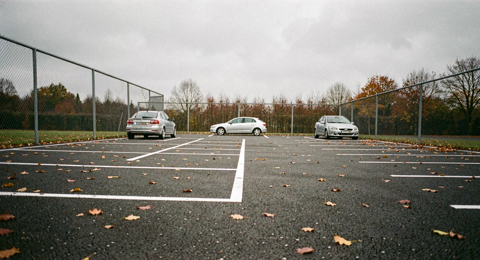 Ogrodzony plac parkingowy z kilkoma autami